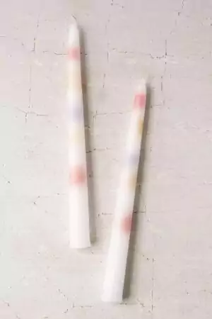 Two multi-color ceromancy taper candles lit and dripping — colorful melted wax pooling for divination reading demonstration.