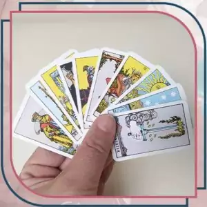 Hand holding a spread of miniature Rider-Waite tarot cards — showing colorful illustrated cards fanned out from the mini pocket edition deck for scale.