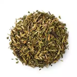 Dried hyssop Hyssopus officinalis cut herb showing finely chopped green and brown plant material mixed in a pile on white background