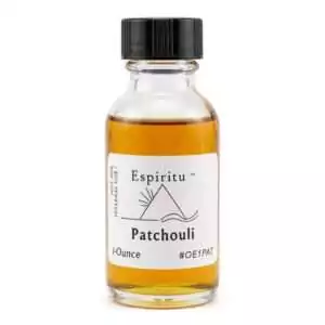 A small glass bottle of patchouli essential oil with a black cap and white label — an Espiritu 1oz ritual anointing oil for prosperity, grounding, and sensuality in magical practice.