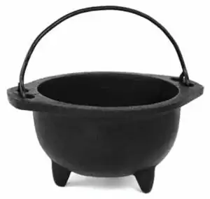 6-inch black cast iron cauldron with fixed iron handle and three sturdy legs, suitable for open-flame ritual use on an altar.