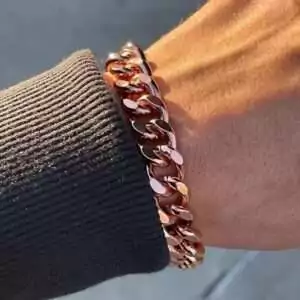 Hand wearing a solid copper heavy link chain bracelet — showing the bold interlocking copper chain design in wear context.
