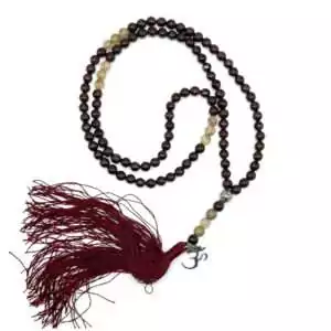 Japa mala necklace with 108 garnet and golden rutile quartz beads and Om symbol guru bead for mantra practice, meditation, and manifestation rituals.