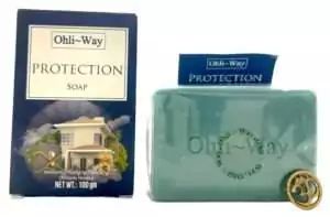 Green bar of Ohli~Way Protection Soap beside its blue box, showing the house illustration and brand label on both.