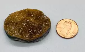 A two-inch Uruguayan amethyst free-form druzy cabochon covered in sparkling deep purple crystal points, organic freeform shape photographed on a white surface.