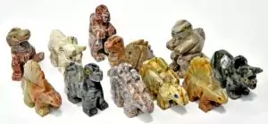 A set of twelve mini dolomite dinosaur figurines, small hand-carved stone creatures in various dinosaur poses, showing natural beige and cream stone coloring.