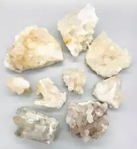 Approximately three pounds of quartz crystal points with natural mineral inclusions, ranging three to six inches, arranged in a flat box on a white surface.