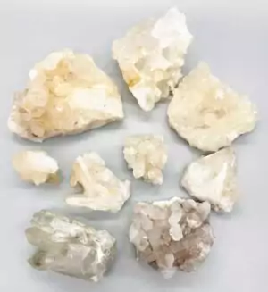 Approximately three pounds of quartz crystal points with natural mineral inclusions, ranging three to six inches, arranged in a flat box on a white surface.