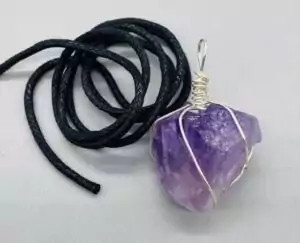 A handcrafted amethyst wire wrapped pendant showing a deep purple amethyst crystal stone intricately wrapped in silver wire as wearable crystal jewelry for intuition work.