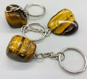 Tiger eye tumbled crystal keychains in various polished shapes with silver key rings — golden-brown chatoyant stone keychains for courage and grounded focus energy.