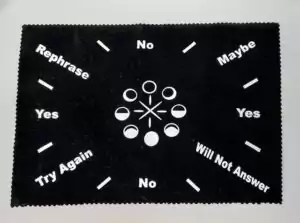 An 8 by 12 inch moon phase pendulum divination mat showing a printed lunar cycle design with directional sections for yes/no and guided pendulum readings.