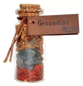 A small grounding pocket spellbottle sealed and labeled with dark earth-toned ingredients, a compact folk magic charm bottle for stability and root chakra grounding.