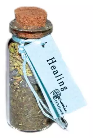 Small corked glass healing pocket spellbottle filled with herbs and crystals for wellness restoration and spiritual comfort ritual