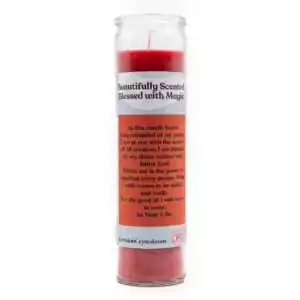 Red scented candle in clear glass container with Magical Manifestation label burning in atmospheric candlelit setting