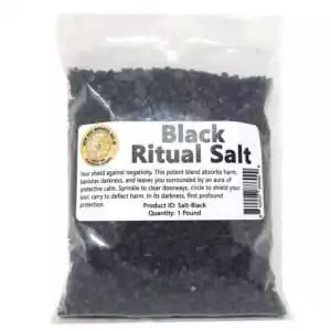 Black ritual salt in a clear plastic bag with a protective-purpose label — a one-pound coarse blend of black salt and herbs by New Age Imports for warding and banishing.