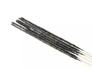 Set of dark black handmade pontifical resin incense sticks arranged in a row with wooden ends visible for sacred ritual ceremony use