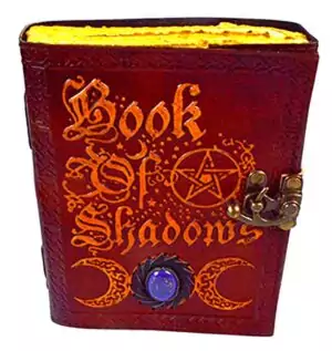 Aged leather-look Book of Shadows journal with metal latch, featuring embossed occult symbolism, for Wiccan grimoire and spell record keeping.