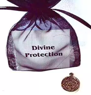 Black drawstring pouch labeled Divine Protection next to a circular pendant amulet with intricate carved designs, for spiritual protection and shielding.