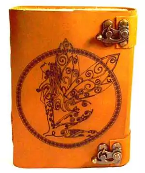 Orange aged leather-look journal with detailed fairy figure embossed within a circular botanical design, secured with decorative metal clasps on the side.