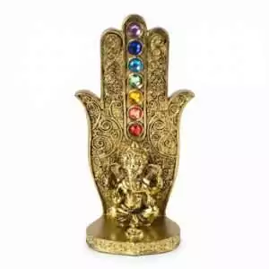 Gold-tone decorative hand incense burner with colorful chakra gemstones along the center and a small Ganesha figurine at the base.