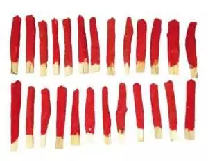 Red sandalwood-dipped palo santo sticks arranged in rows showing their aromatic coating for grounding ritual smudge use.