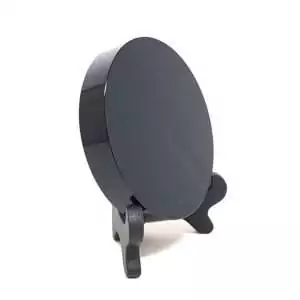 Round black obsidian scrying mirror displayed on a small wooden stand, polished surface for divination and vision work
