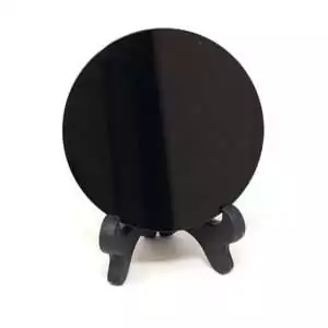 Black obsidian scrying disc on small stand with smooth reflective surface used for gazing and intuitive divination practice