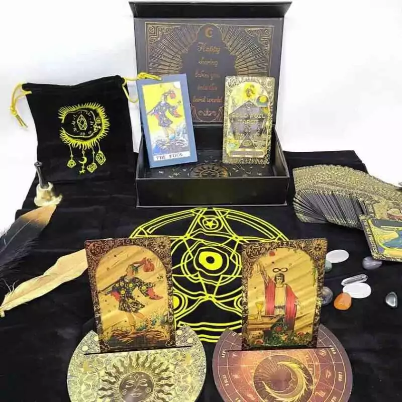 Rider-Waite black and gold foil tarot cards displayed on black cloth with crystals, a feather, and a decorative box showing mystical tarot imagery.
