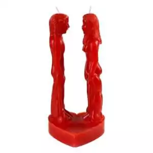 Red wax candle sculpted as two stylized figures facing each other on a heart-shaped base, for hoodoo passionate love and reunion ritual burning.