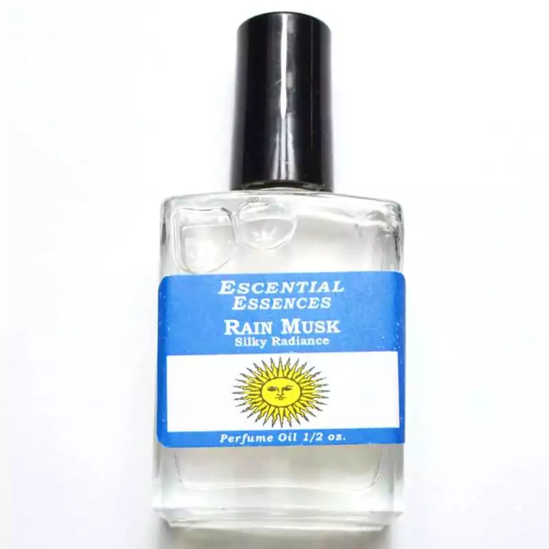 Rain Musk fragrance oil half oz — clear glass bottle with blue and white label featuring sun graphic, Escential Essences Rain Musk 0.5 oz perfume oil.