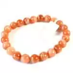Eight millimeter sunstone beaded stretch bracelet with warm orange and golden glittering aventurescence stones on a white surface