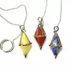 Double-terminated gemstone pendulum with pointed ends in a mixed natural stone, hanging from a metal chain on a white background
