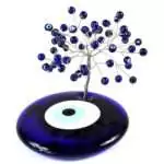 Wire bonsai gemstone tree sculpture with blue evil eye nazar beads and small crystal chips wired onto branch tips, shown on plain background