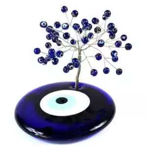 Wire bonsai gemstone tree sculpture with blue evil eye nazar beads and small crystal chips wired onto branch tips, shown on plain background