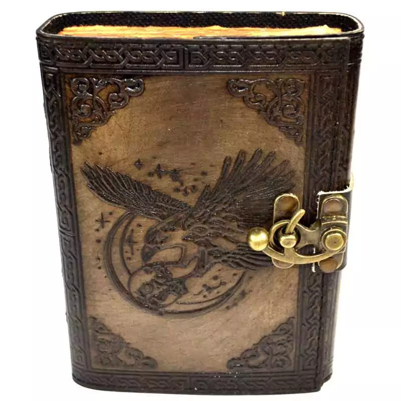 Dark brown faux leather journal with embossed raven perched on a skull design on the cover, metal latch closure, aged parchment-style interior pages