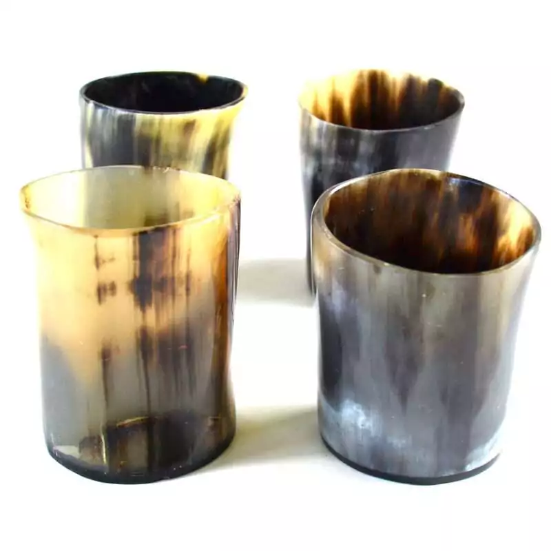 Set of four small bone-carved shot glasses for ritual libation offerings, arranged together on a plain surface