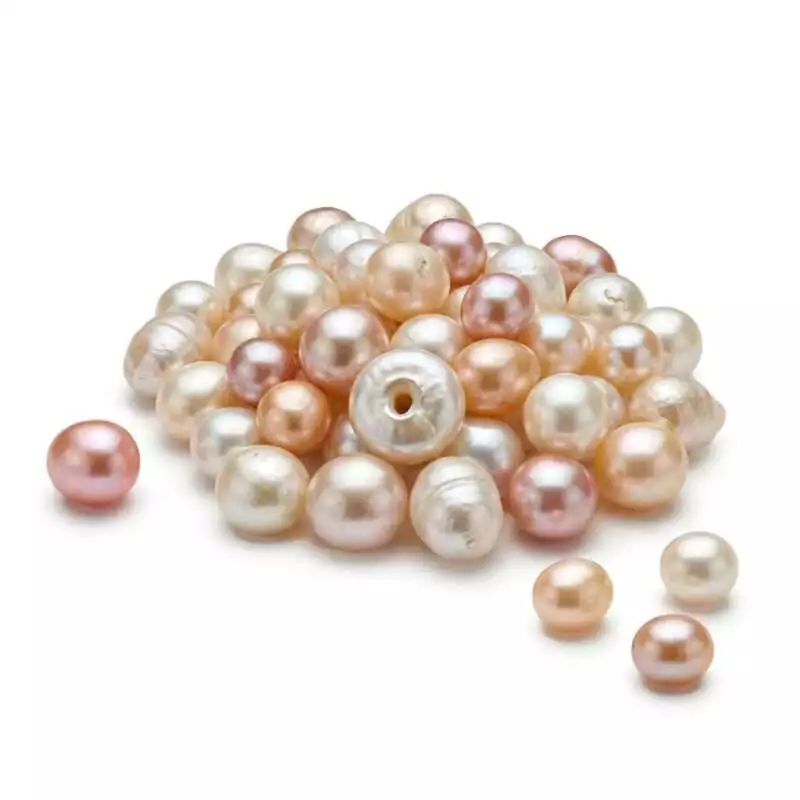 100gms-10-17mm-Pearls-GSPEA100_Z 100 grams of loose natural cream-toned pearl beads ranging 10 to 17mm in size, displayed in a pile or spread showing varied oval and round shapes on a white background
