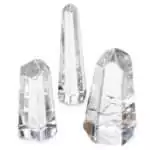 Small polished clear quartz obelisk tower measuring 1 to 1.5 inches, showing transparent crystalline structure with a pointed tip on a white background