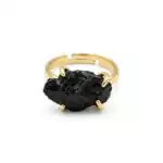 Adjustable black tourmaline ring with rough dark stone set in silver-tone open band, shown on neutral background.