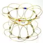 A 5-inch brass wire mandala meditation puzzle in an open bowl configuration, showing its delicate interconnected wire structure with small colorful bead accents and a warm gold tone.