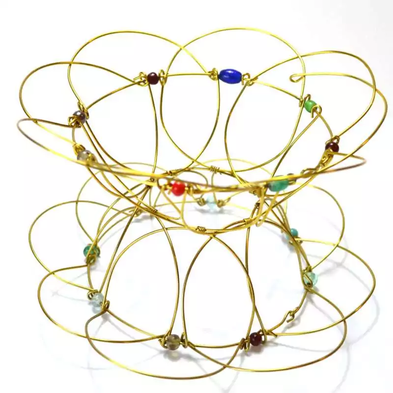 A 5-inch brass wire mandala meditation puzzle in an open bowl configuration, showing its delicate interconnected wire structure with small colorful bead accents and a warm gold tone.