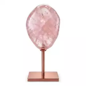 Natural pale pink rose quartz crystal specimen mounted on a warm copper-toned display stand against a white background showing soft blush mineral surface