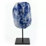 Natural deep blue sodalite crystal with white calcite veining mounted on a matte black display stand against a white background