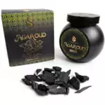 Black jar of Sonavi Agar Oud bakhoor incense chips next to its decorative box, with small dark agarwood chips scattered about — 40g natural agarwood resin blend.