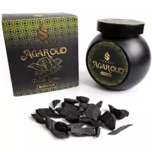 Black jar of Sonavi Agar Oud bakhoor incense chips next to its decorative box, with small dark agarwood chips scattered about — 40g natural agarwood resin blend.