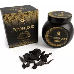 Black jar of Sonavi Amber Oud bakhoor incense chips with decorative gold lid, next to its matching box, with small oud wood pieces scattered on the surface — 40g warm amber and oud resin blend for ritual and meditation.
