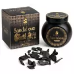 Black jar of Sonavi Sandal Oud bakhoor incense chips with gold label, next to its decorative box with intricate designs, and small oud wood pieces scattered in front — 40g natural sandalwood and agarwood grounding blend.
