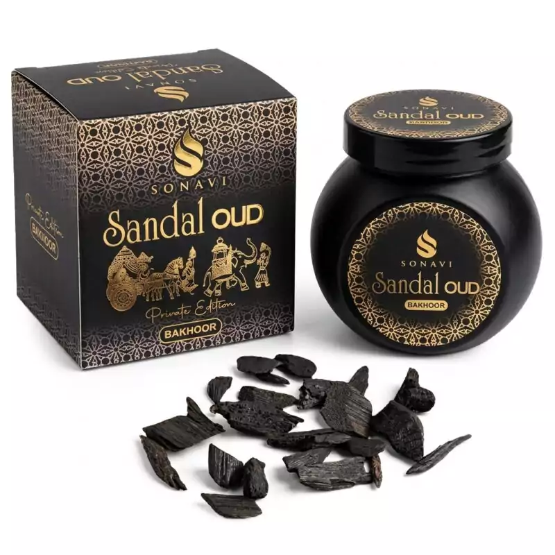 40gms-Sandal-Oud-Sonavi-IBESD40_Z Black jar of Sonavi Sandal Oud bakhoor incense chips with gold label, next to its decorative box with intricate designs, and small oud wood pieces scattered in front — 40g natural sandalwood and agarwood grounding blend.