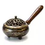 9-inch metal incense burner with antiqued golden finish, intricate swirling pattern on the decorative metal top, and wooden handle — compact charcoal and resin censer for ritual space clearing and altar use.