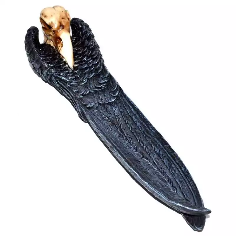10quot-Raven-Skull-incense-holder-IB3541 Cold cast resin incense holder shaped as a black raven skull with pale bone-colored beak and spread wings extending down its 10-inch length, forming an ash-catching channel.